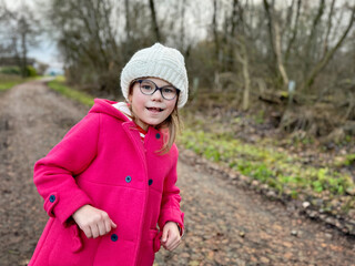 Portrait of a cute school girl with eyeglasses outdoors in park. Happy funny child on autumn,...