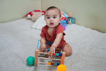 Happy baby with a colorful wooden toy maze, highlighting early childhood development and sensory...