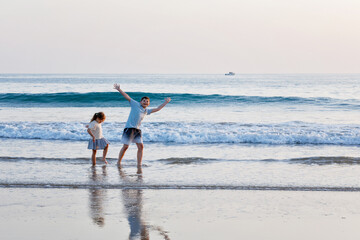 Two children on ocean beach. Teenager boy and little preschool sister having fun by sunset. Sea...