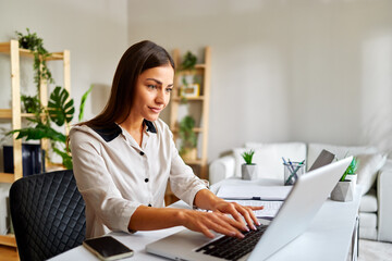 Businesswoman working remotely using laptop and concentrating on her project