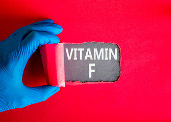 Vitamin F symbol. Concept words Vitamin F on beautiful grey paper. Doctor hand in blue medical...