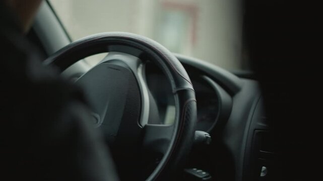 Back view of car buff driving, skillfully turning steering wheel to execute smooth turn, blurred street scene visible through window, capturing driver focus, control and urban commute vibe