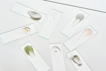 Texture samples of various cosmetic products on a gray background.