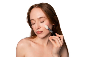 Woman applying makeup with a makeup brush in a bright, minimalistic setting during a beauty routine