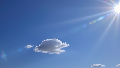 the sky is a clear blue with bright sunlight filtering through to create lens flares. there is one small cloud in the upper right corner of the frame.