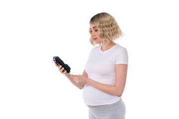 Expecting mother reviews a digital device with curiosity while standing indoors in light clothing...