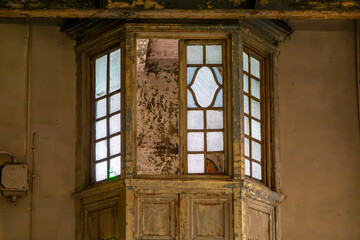 Obraz premium Weathered wooden observation booth with stained glass windows, built into the wall of an old, decaying building. Peeling paint and signs of neglect emphasize a vintage, abandoned atmosphere.