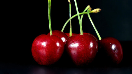close up of group of red cherries on black background