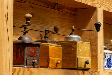 Vintage manual coffee grinders displayed on a wooden shelf in a rustic interior. Charming retro decoration evoking tradition and old-style craftsmanship, perfect for kitchen and nostalgic themes.