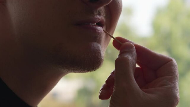A man brushes his teeth with a toothpick close-up.
Oral care.
Cleaning teeth after eating with a toothpick and dental products
