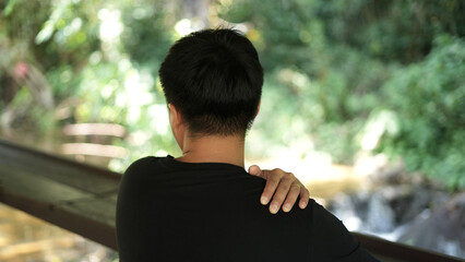 A young asian man athlete with lower backache, neck pain and shoulder pain, injury or strained...
