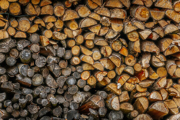 A close-up view of chopped and stacked firewood in various shades, textures, and sizes, showcasing...