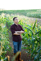 Young man farmer standing in corn field