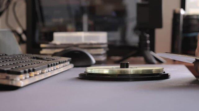 Close-up of hand stacking CDs beside keyboard, retro digital archive scene in nostalgic workspace.
