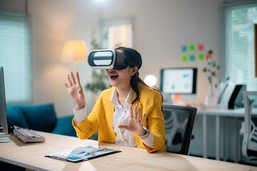 Asian businesswoman wearing vr headset is enjoying virtual reality experience and gesturing with hands in modern office