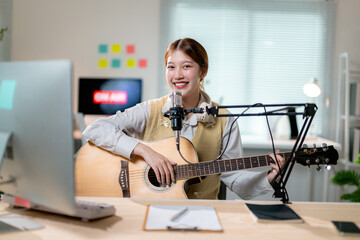 Asian woman vlogger artist influencer playing guitar and live streaming online for audience