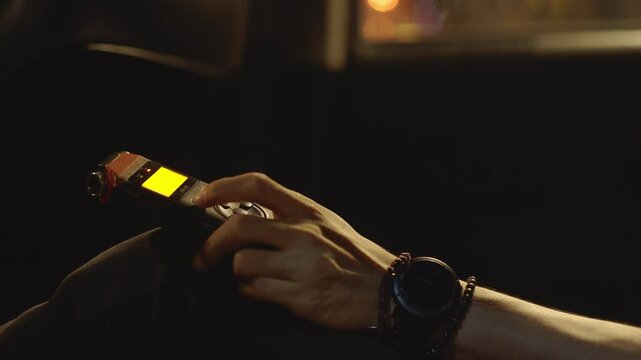 Close-up of Hand Using Portable Digital Audio Recorder in Dark Setting