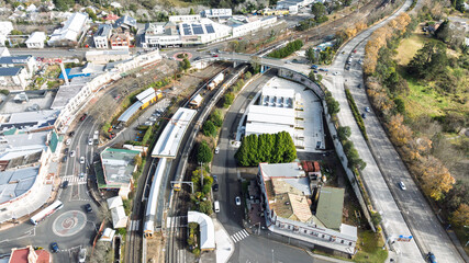 Drone aerial photograph of a train arriving and departing at the Katoomba Train Station near the Great Western Highway in the Blue Mountains, NSW, Australia.