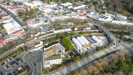 Drone aerial photograph of a train arriving and departing at the Katoomba Train Station near the Great Western Highway in the Blue Mountains, NSW, Australia.
