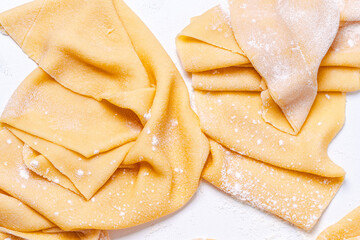 Pasta dough rolled out for naming on a white table. The process of making handmade spaghetti.