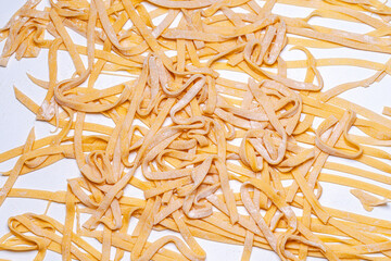 Obraz premium Handmade raw pasta, spaghetti on a white table. Background with raw spaghetti texture. Close-up, top view.