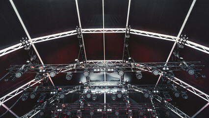 Professional stage lighting rig installed under a black canopy with multiple LED spotlights, moving...