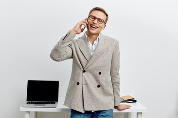 Smiling author man in trendy blazer talking on smartphone during work from home in modern office...