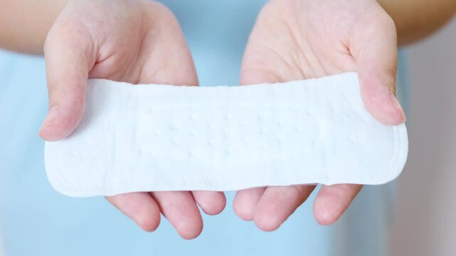 Woman confidently displaying sanitary pad, emphasizing menstrual health awareness, personal hygiene, and women's wellness during monthly cycle