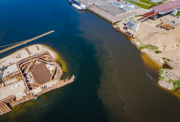 Construction site of new modern bridge construction in Kaunas, Lithuania. Aerial drone view of bridge connecting two shores of a river. Work progress