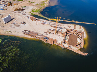 Construction site of new modern bridge construction in Kaunas, Lithuania. Aerial drone view of bridge connecting two shores of a river. Work progress