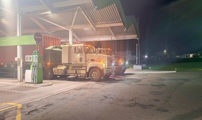 Military convoy on a road in Europe. Military armoured convoy at a petrol station. Movement of a military convoy to a military exercise within Europe. Defence and preparation for armed conflict.