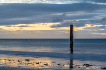 old wooden post in the sea at Swanage Dorset England at sunrise with the sea blurred in the...