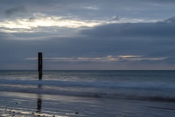 old wooden post in the sea at Swanage Dorset England at sunrise with the sea blurred in the...