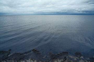 calm sea water with horizon, cloudy sky, summer evening