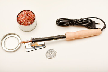 A soldering iron with a wooden handle with solder and a stand. Soldering iron and stinger cleaner.