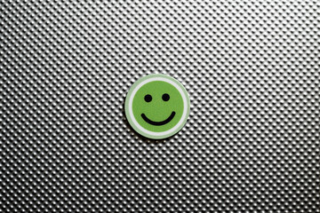round emoji face in green color, representing happy emotions on a metallic textured background,...