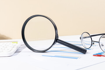 Fototapeta premium Financial Charts and Graphs Analyzed with Magnifying Glass, Calculator, and Pen – Business Insight Concept