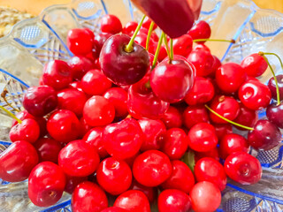 Background filled with a close-up of ripe dark burgundy cherries in glass plate