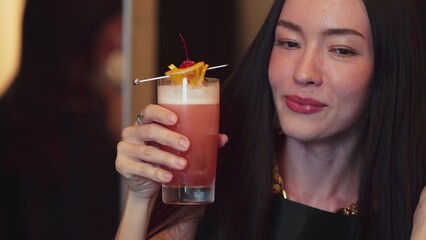 Smiling beautiful woman zipping cocktail in Paloma drinks smoothy garnished with cherry lemon...