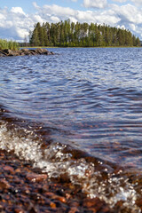 Siljan lake clear water pebbles shore waves, in Isunda, Dalarna, Sweden. Isundaholmen island with...