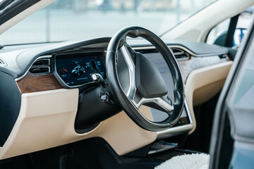 Closeup view of a modern black and white luxury car interior with steering wheel and digital...