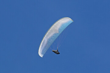Paraglider flying in a blue sky	