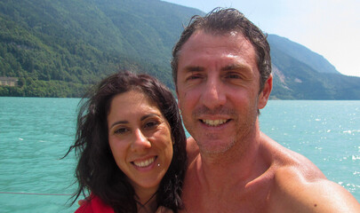 Obraz premium Husband and wife on a pier overlooking Lake Molveno in Trentino, Northern Italy. The man and woman are forty years old and are of Sicilian origin