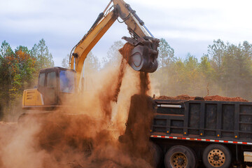 Heavy machinery moves dirt debris while creating construction site in wooded landscape under works...