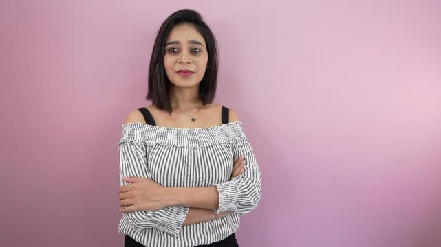 Confident Sunanda Malam woman stands with arms crossed against a pink background