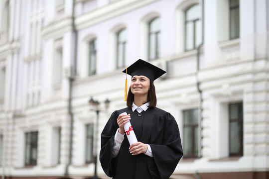 A happy graduate in cap and gown smiles and celebrates, the concept of education