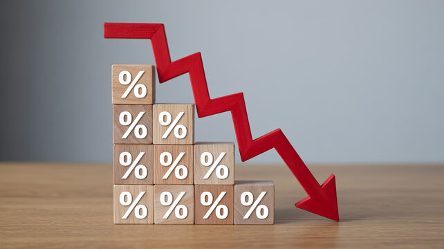 Interest Rate Decline: Symbolic representation of falling interest rates, featuring wooden blocks with percentage symbols and a downward-pointing red arrow, indicating a decrease in financial metrics.