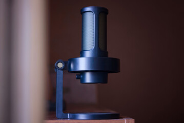 Close-up of a professional black condenser microphone mounted on a desktop stand with a smooth bokeh background, ideal for high‑quality audio projects. Photo. High resolution