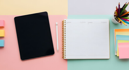 Overhead view of a tablet, stylus, notebook, colorful pencils, and sticky notes arranged on a pastel-colored split background.