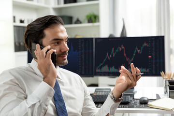 Trader businessman calling to consultant or partner with two stock exchange investment, compare...
